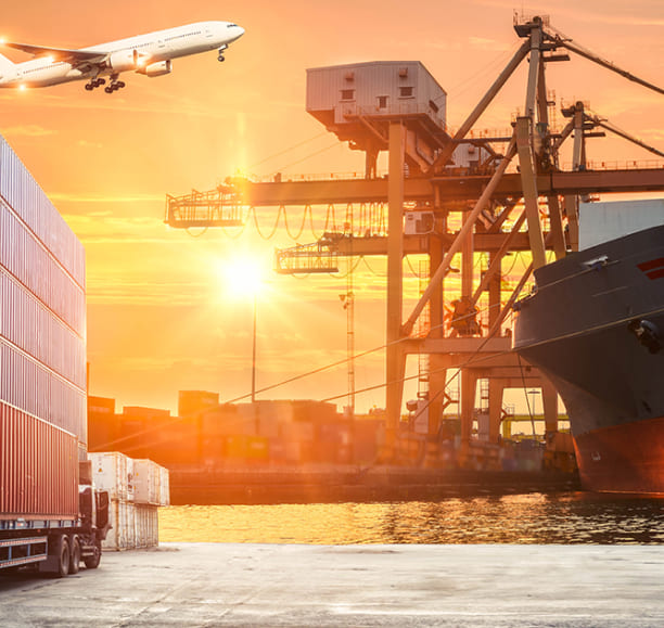 Foto ilustrativa de um navio atracado no porto, containers e um avião voando